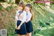 Two young women in school uniforms standing next to each other.