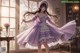 A woman in a purple dress is dancing in a room.