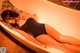 A woman in a black bathing suit laying in a bathtub.