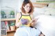 A woman sitting on a bed reading a book.