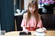 A woman sitting at a table with a cup of coffee.