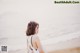 A woman standing on a beach next to the ocean.