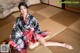 A woman in a kimono sitting on a tatami mat.